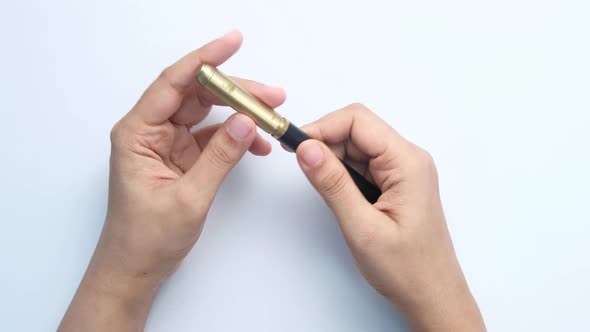 Top View of Women Hand Holding Fountain Pen on White Background .