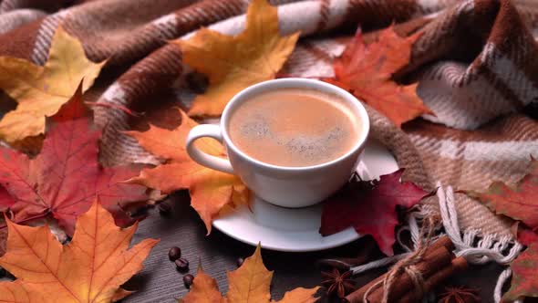 Autumn Fall Leaves Hot Cup of Coffee and Warm Plaid on a Wooden Table Background