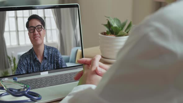 Close-Up Of Doctor Talking To Patient Over Laptop Video Chat At Desk
