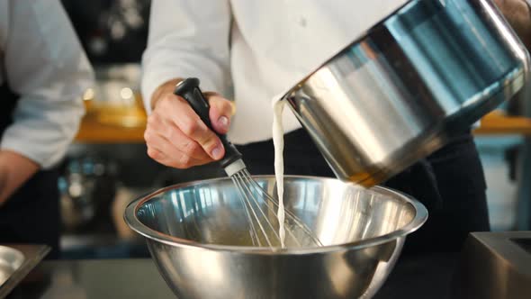 Milk is churned in a professional restaurant kitchen. Dessert cooking.