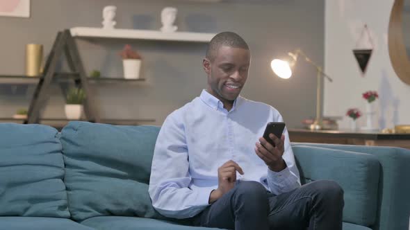 Attractive African Man Using Smartphone on Sofa