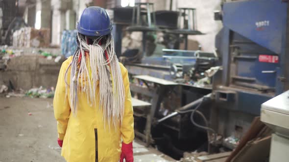 Womanworker with Dradlocks in Yellow and Transparent Protecting Glasses Hard Hat and Mask Working