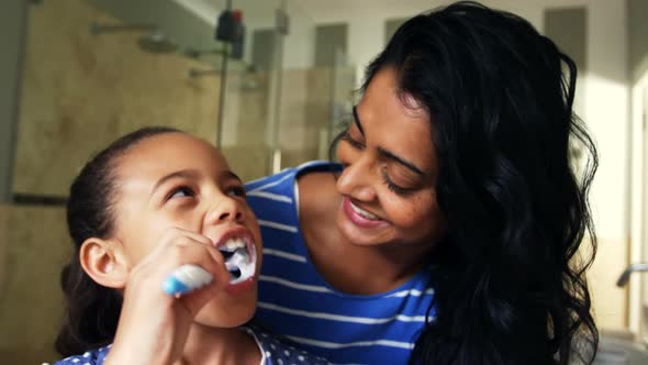 Mother teaching her daughter to brush her teeth in bathroom 4k