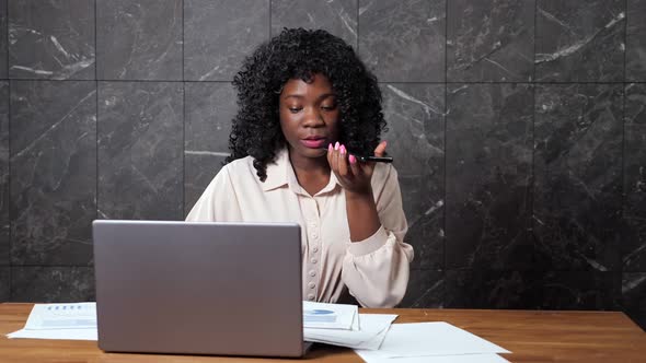 Afroamerican Businesswoman Talks on Phone Looking at Graphs