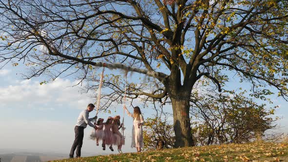 Mother and father swinging their daughters