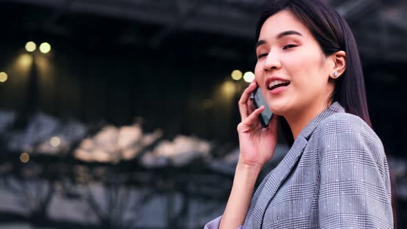 young asian woman is looking down at her mobile phone happily