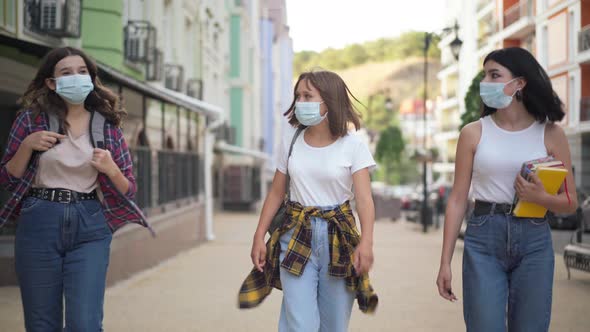 Portrait of Three Caucasian College Students in Covid Face Masks Strolling on City Street with
