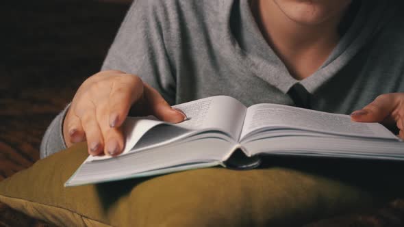 Cute Girl Reads and Leafs Through a Book While Lying Comfortably in Bed