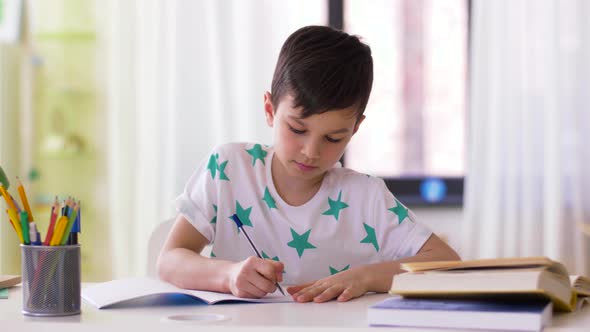 Boy Writing To Notebook at Home