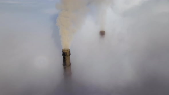 Coal Power Plant High Pipes Emitting Black Poisonous Smoke Moving Upwards Over White Fog Polluting