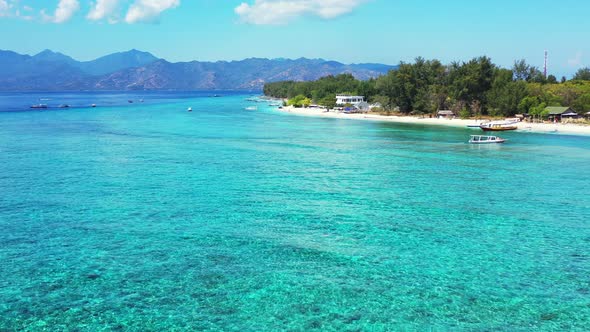 Daytime above island view of a sunshine white sandy paradise beach and blue ocean background in colo