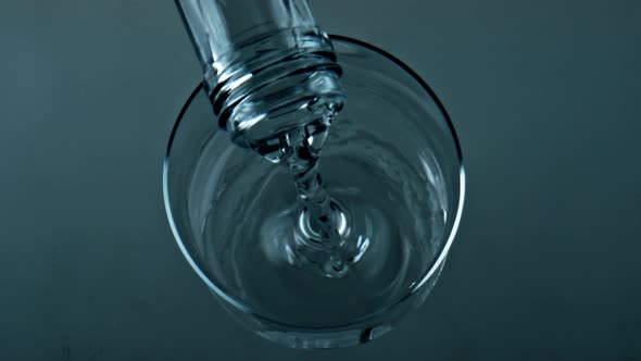 Bottle Pouring Pure Water Into Transparent Cup Closeup