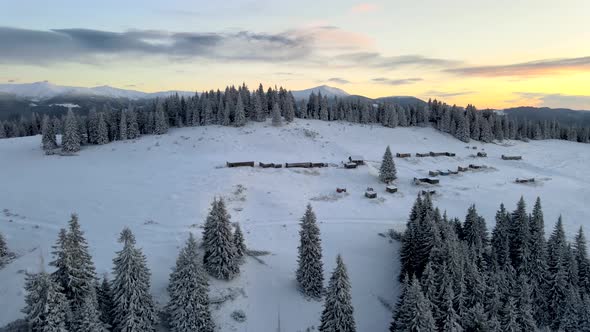 Drone Rising Above Village Unveiling Mountain Range at Sunrise