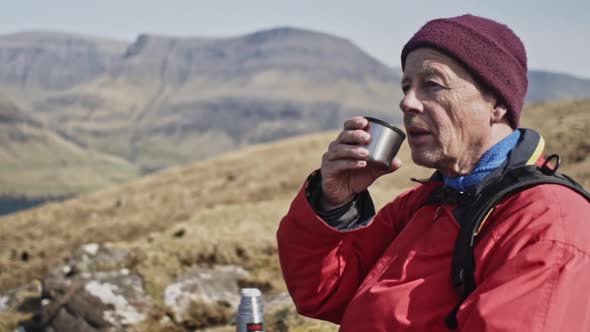 Male Traveler Drinking From His Traveler Cup Bottle and Scenic View of Mountain