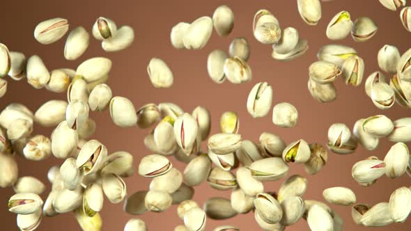 Super Slow Motion Shot of Flying Pistachios After Being Exploded on Brown Background at 1000Fps