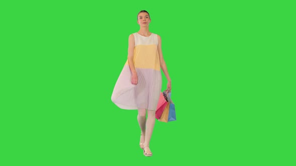 Young Girl Walking in Summer Dress Holding Shopping Bags on a Green Screen Chroma Key