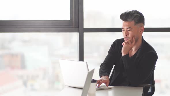 Portrait of a Chinese Businessman Sitting at the Office Table in the Evening