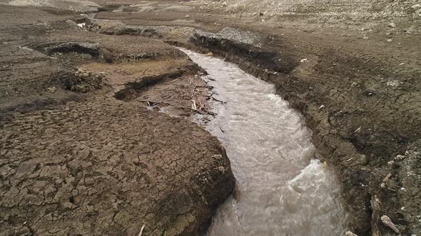 Narrow river flowing and dividing dried ground