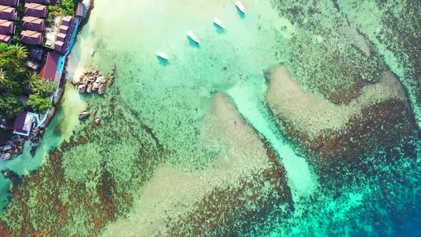 Aerial drone shot landscape of idyllic seashore beach holiday by blue ocean with white sand backgrou