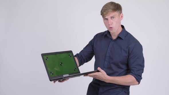 Happy Young Handsome Businessman Showing Laptop and Looking Surprised