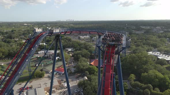 Kids and teenagers having fun riding an extreme roller coaster in theme park. Aerial view