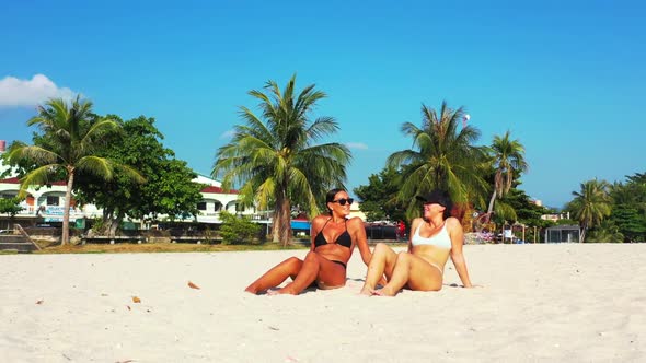 Women enjoying life on marine sea view beach holiday by aqua blue water with bright sand background 