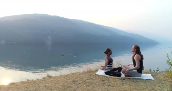 Friends performing yoga near lakeside 4k