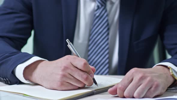 Businessman Writing in Notebook