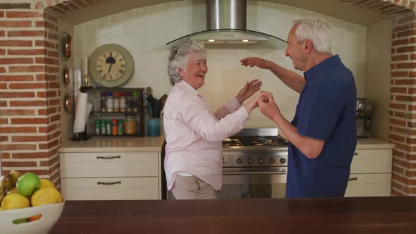 Senior caucasian couple dancing in kitchen in slow motion