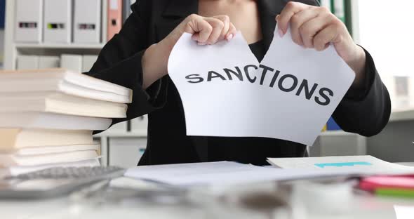 Person Tearing Paper with Word Sanctions Closeup