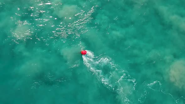 A marine navigational buoy swaying in a fast tidal current along a sandy section of water