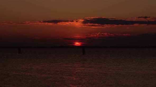 Dark Sea Under Sun Disk Hiding Behind Cloud Silhouettes