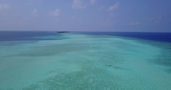 Wide angle fly over island view of a sandy white paradise beach and blue water background in vibrant