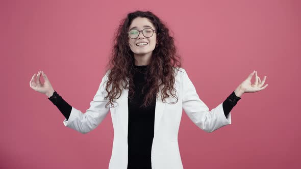 Calm and Balanced Young Woman with Curly Hair is Inspired By Holding Her Hands in the Shape of Yoga