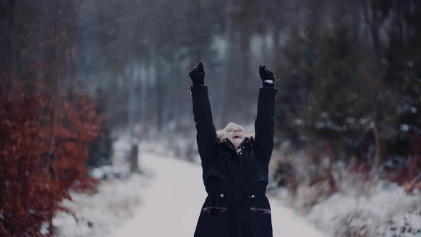 Positive Woman Jumping on Snow and Playing with Scarf in Winter