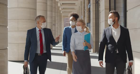 Multi Ethnic Businessmen and Businesswoman Walking Down Street at Business Center in Medical Masks