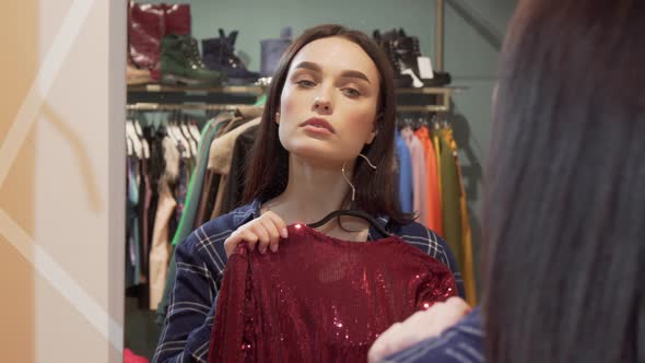 Beautiful Woman Choosing Between Two Dresses, Shopping at Clothing Store