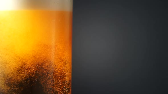 Cold Beer in a Glass Bottle with Dripping Condensation Drops and Air Bubbles