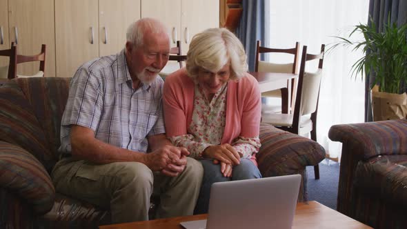 Senior couple in social distancing using laptop