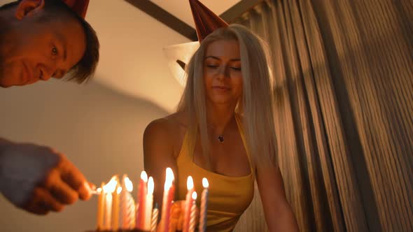 Sexy Hot Blond Girl Look at Man Lighting Candles on Birthday Cake.