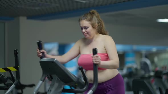 Charming Smiling Overweight Woman Exercising on Air Walker in Gym Indoors