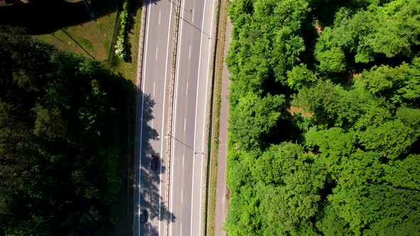 4K Aerial View Of Cars On Highway Overpass With Green Forest Next To It.