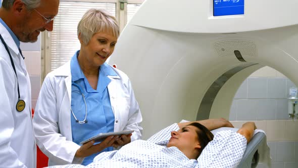 Doctors explaining diagnosis to female patient on digital tablet before mri scan