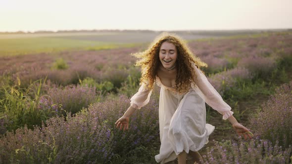 Woman with a Pink Dress Running Joyfully Through a Lavender Field and Smiling