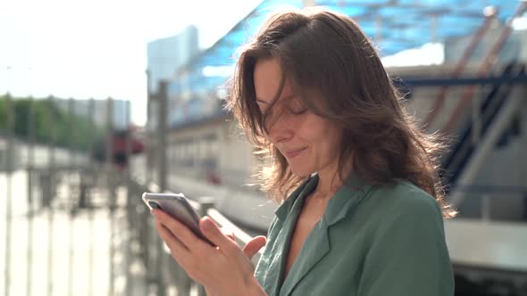 Portrait of a Middle-aged Brunette in a Green Dress. She Stands on a City Street and Checks Her