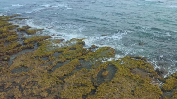 Drone view of waves on Bai Bang beach, with moss covered on rocks, Phu Yen province, central Vietnam