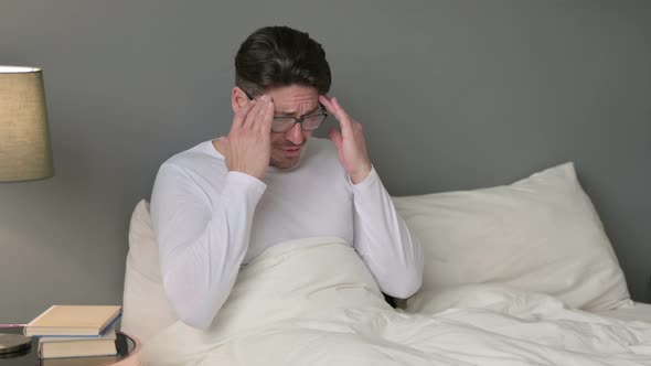 Stressed Middle Aged Man with Headache in Bed 