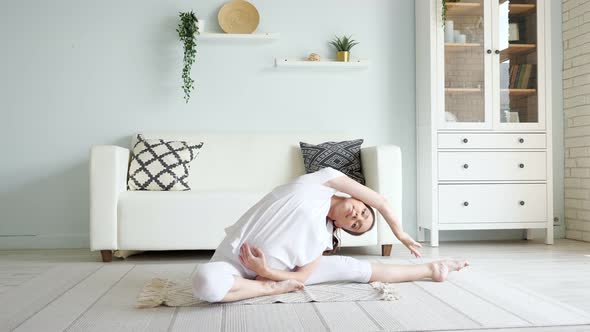 Pregnant Lady Does Janu Sirsasana Sitting on Floor at Home