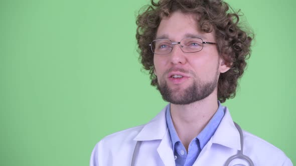Face of Happy Young Bearded Man Doctor Thinking