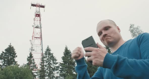 4G and 5G Cellular Radio Tower a Man with Phone is Standing Next to Him